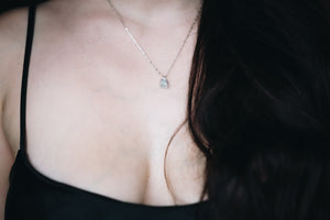 Woman wearing silver chain necklace with broken silver pendant