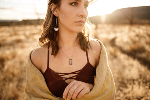 Female model wearing long silver drop earrings with Madagascar spessartine garnets