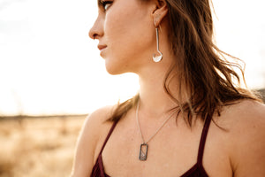 Woman wearing long silver and garnet drop earrings and necklace
