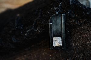 Close up of Curved Corner black and sterling silver necklace pendant from Zink Metals Broken Silver Collection