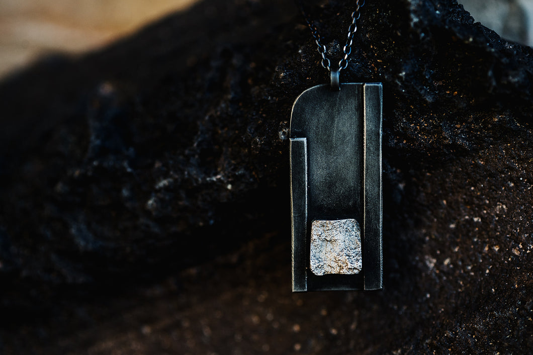 Close up of Curved Corner black and sterling silver necklace pendant from Zink Metals Broken Silver Collection